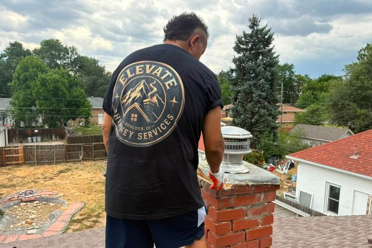 An Elevate Chimney technician at the top of a Boulder brick chimney, where every load of firewood eventually leaves the house