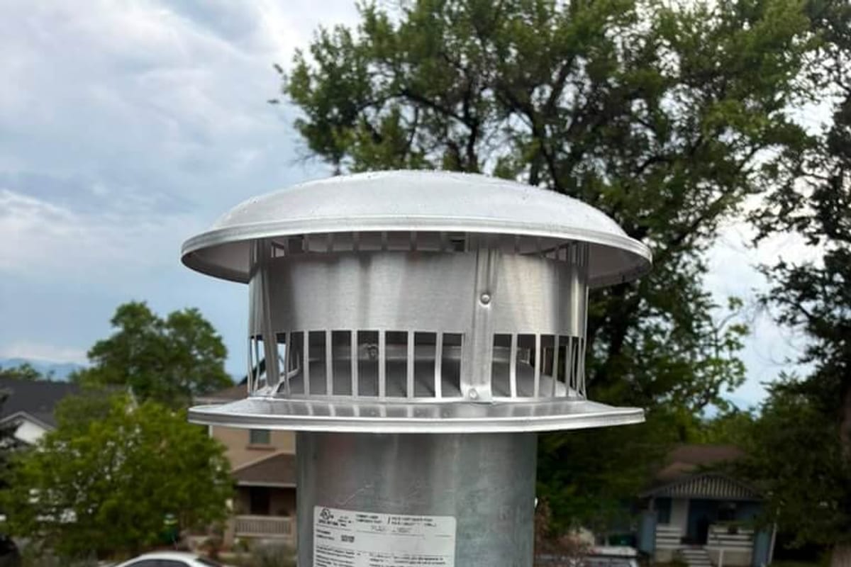 The louvered mesh band on a new galvanized chimney cap, which is the spark arrestor that catches embers from resinous wood